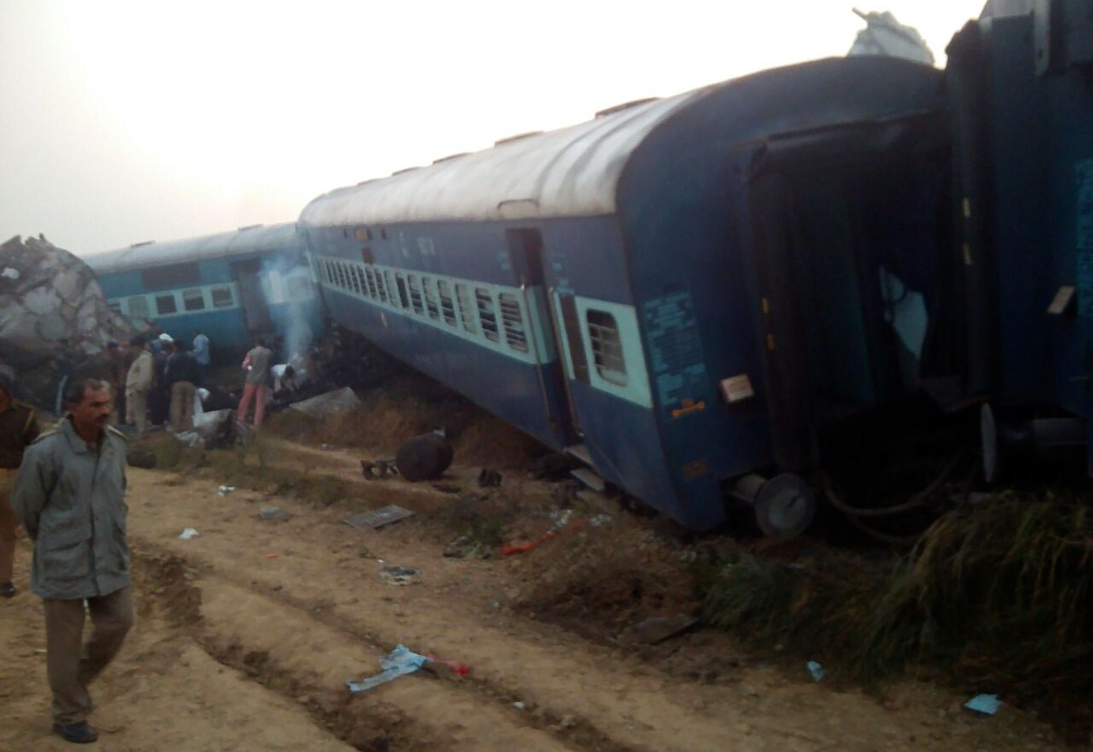 A man walks past the wreckage of an Indian train that derailed near Pukhrayan in Kanpur district on November 20, 2016. A passenger train derailed in northern India on November 20, killing at least 63 travellers most of whom were sleeping when the fatal accident occurred, police said. Rescue workers rushed to the scene near Kanpur in Uttar Pradesh state where the Patna-Indore express train derailed in the early hours of the morning. / AFP / -